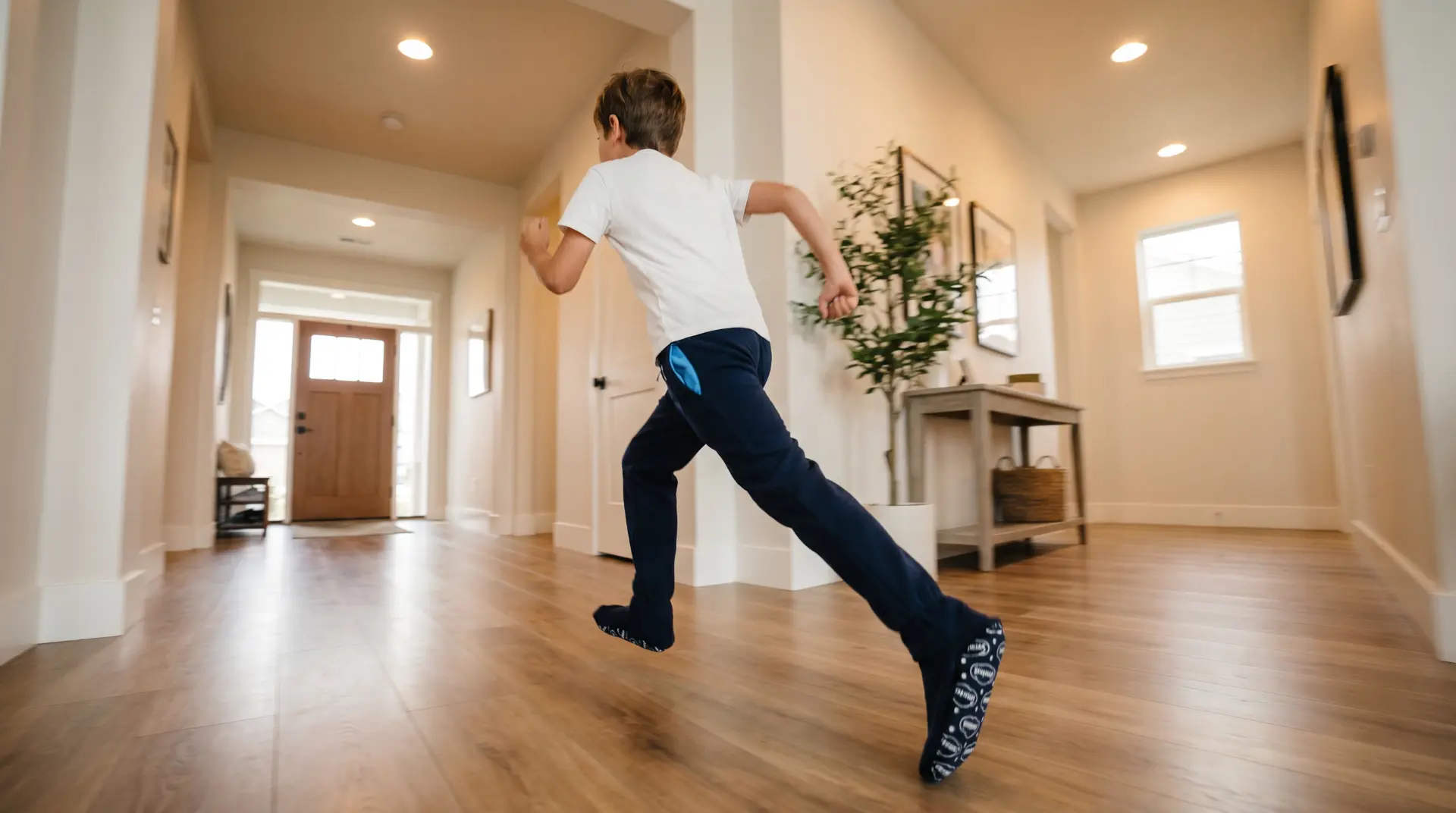 Kid running down a hallway in navy Sweatzies with Sky Soles